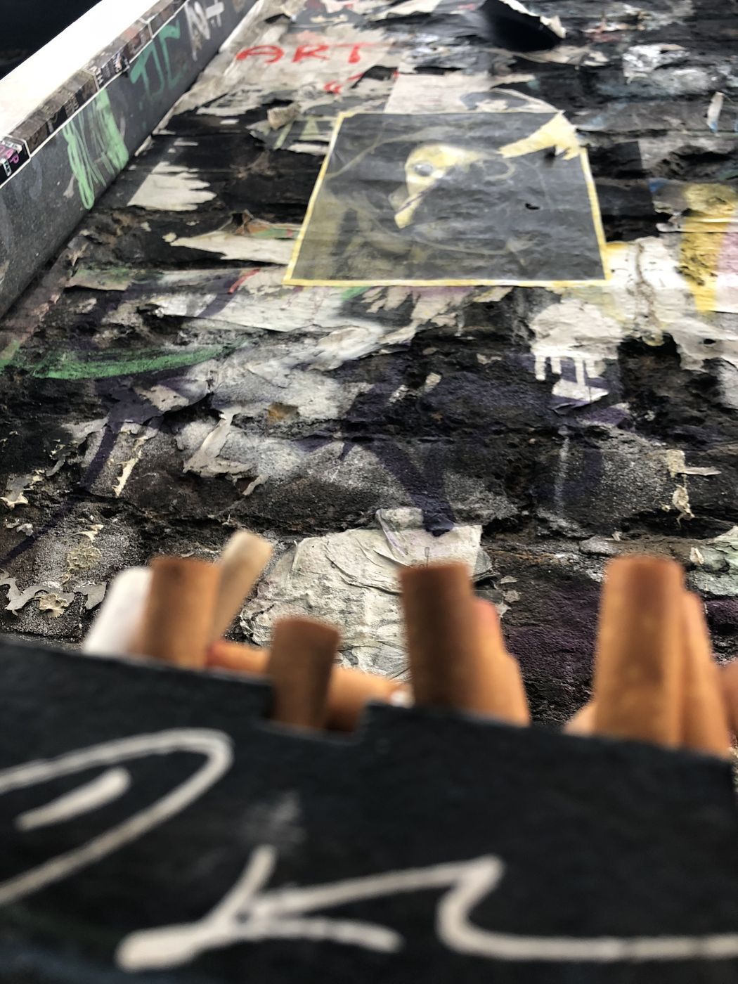 Wall of torn, layered posters and paint forming an accidental collage