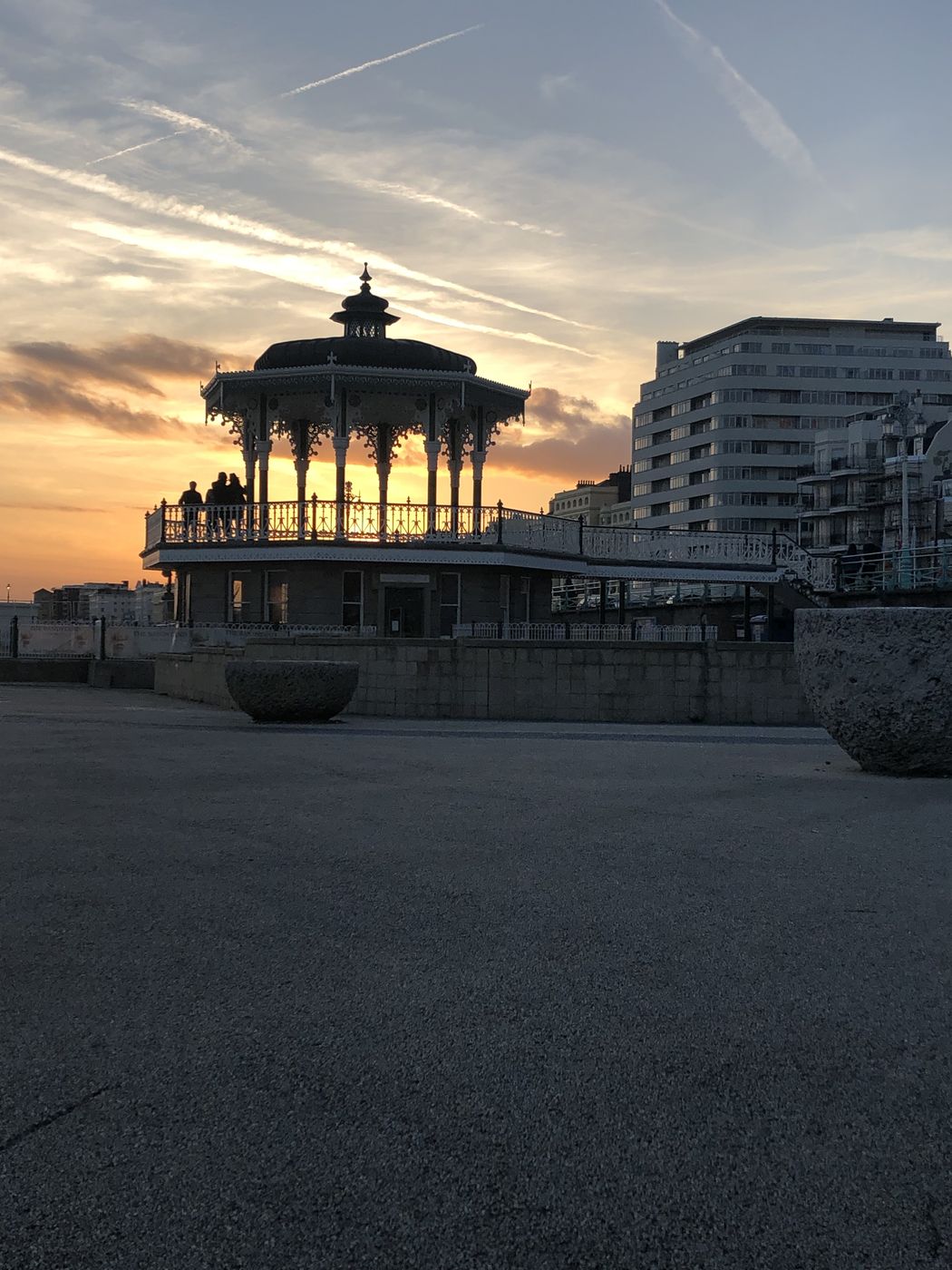 Ornate Victorian bandstand silhouetted against an orange sunset sky