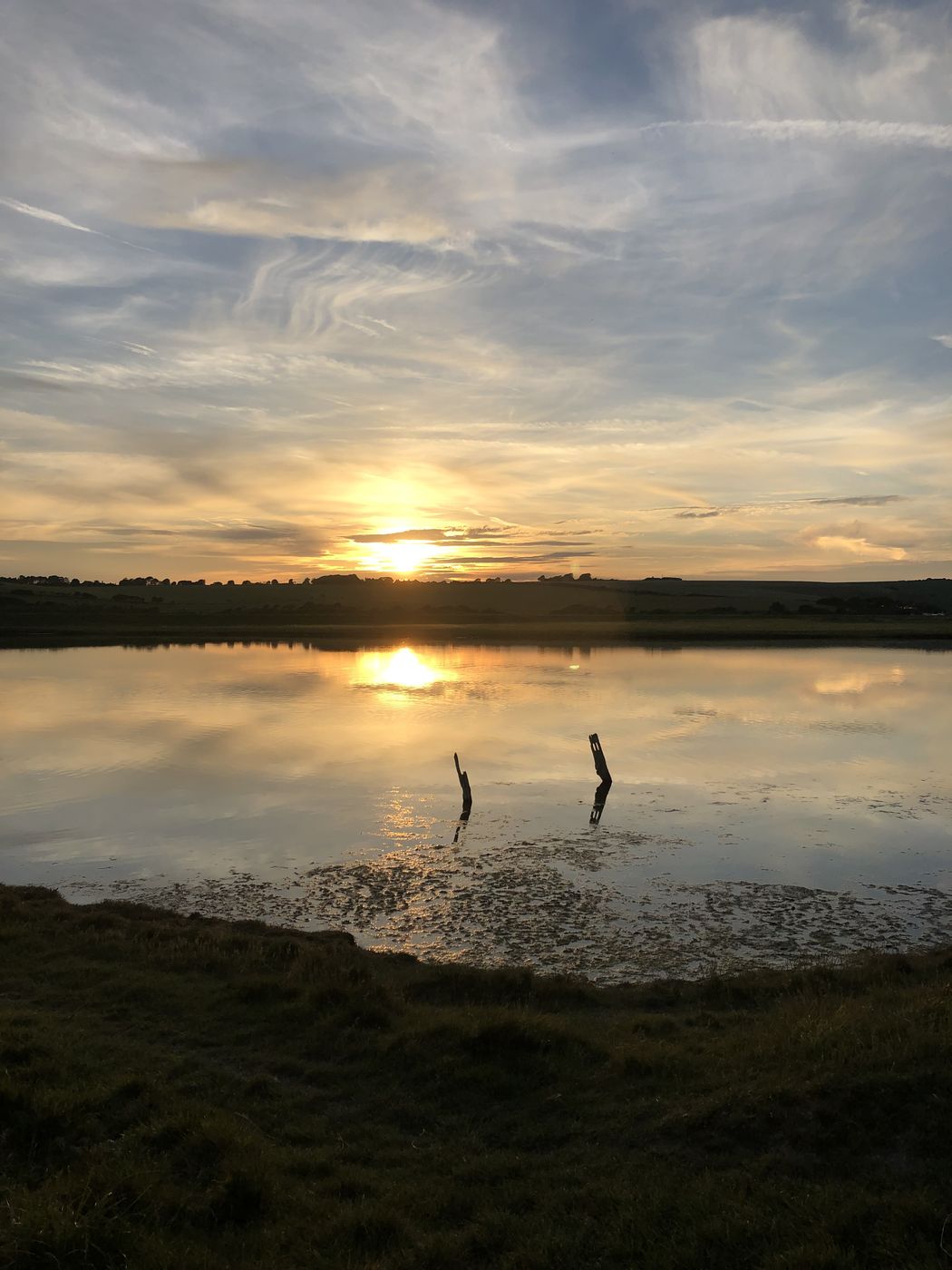 Sun setting over still water with a heron silhouetted in the shallows
