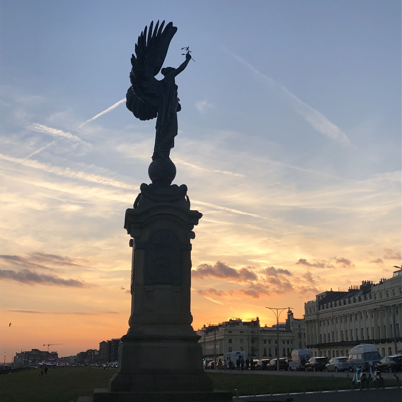 Winged statue holding an olive branch against golden clouds