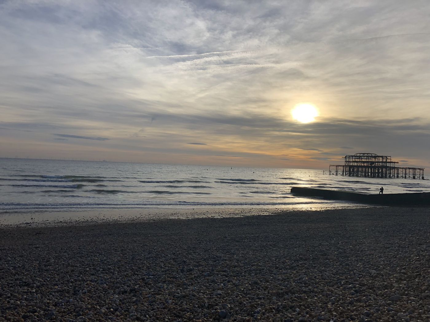 Ruined west pier standing in the sea under a hazy golden sun