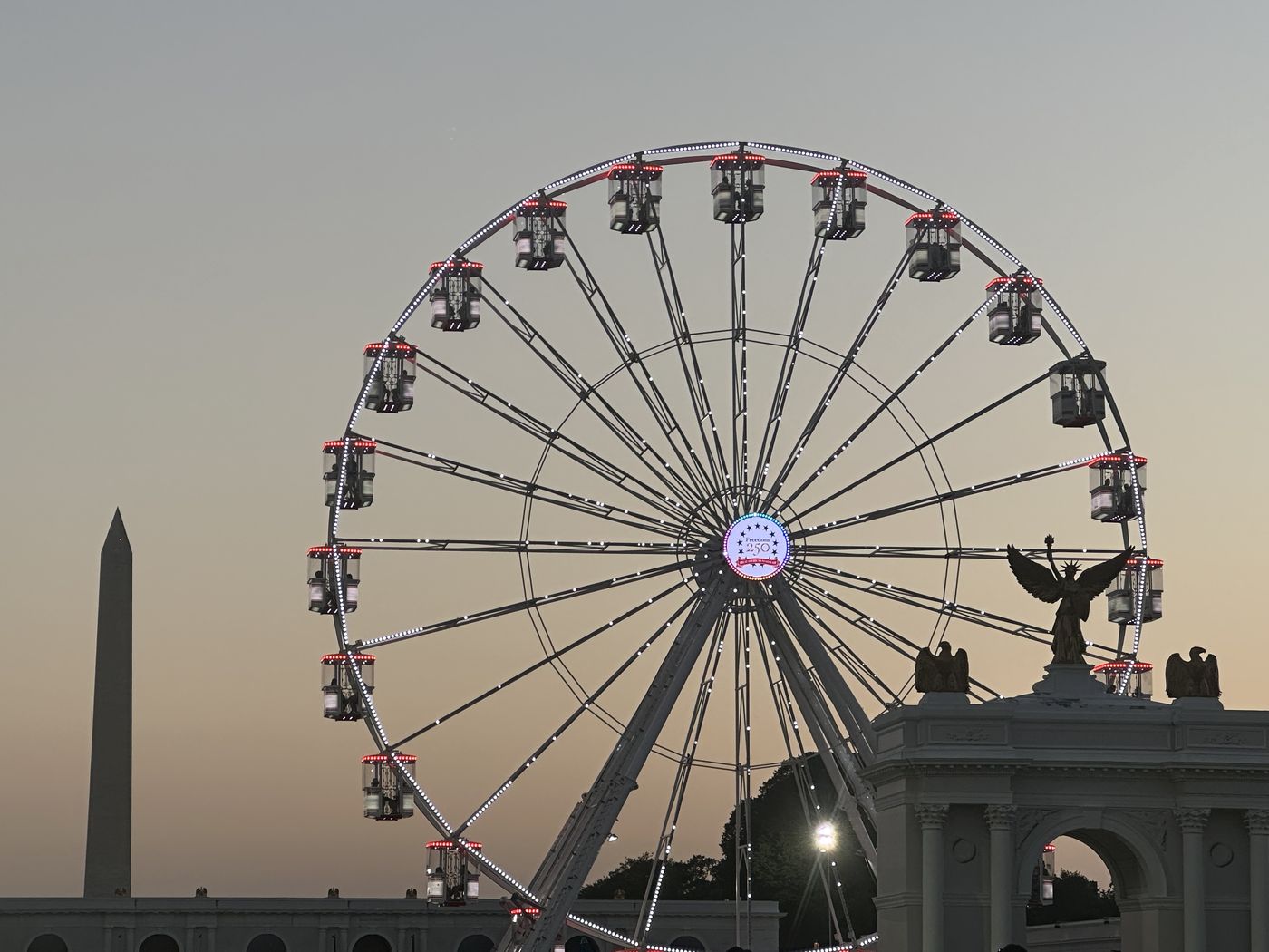 Ferris wheel and Washington Monument silhouetted together at dusk