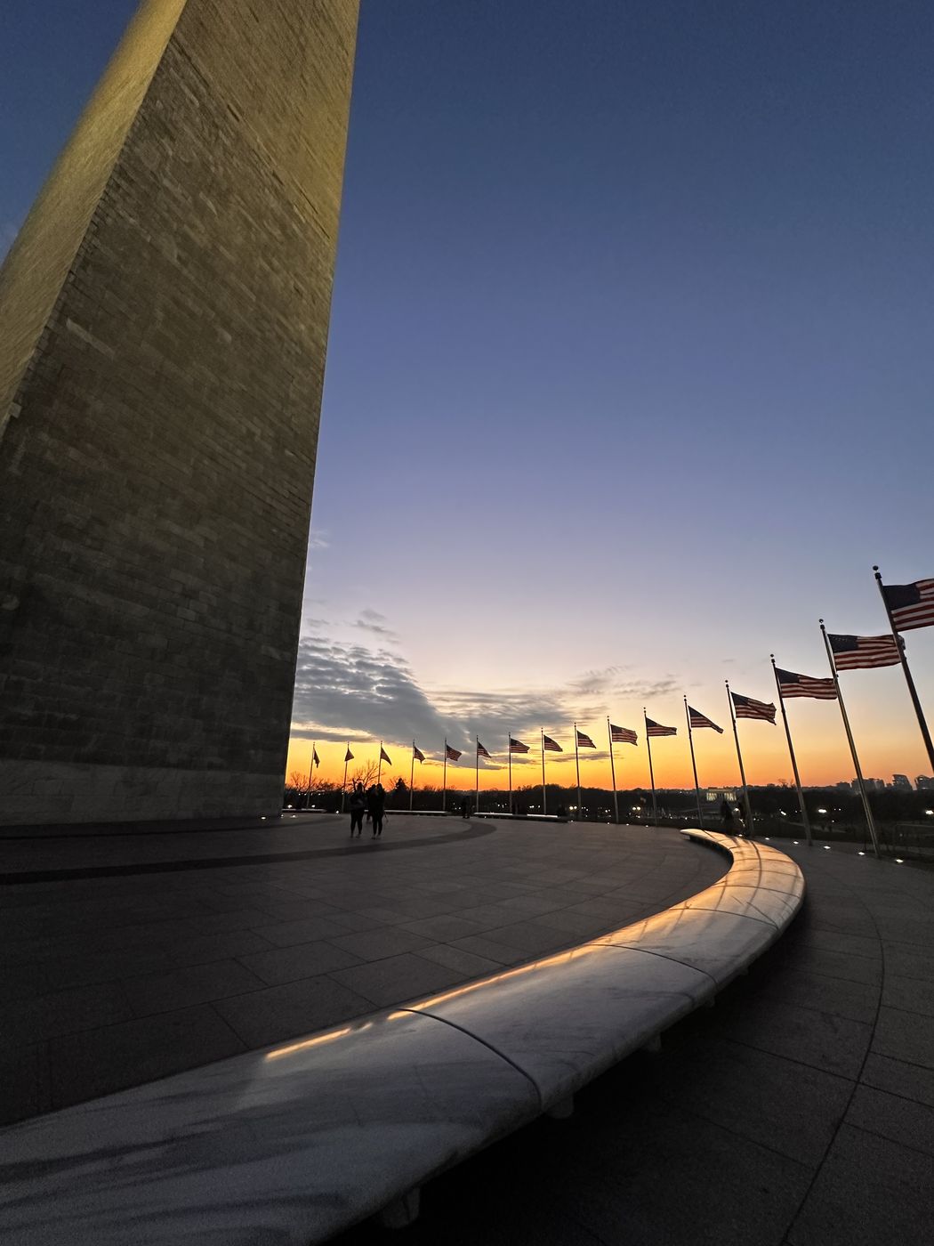 Curved stone bench leading toward the Washington Monument at sunset