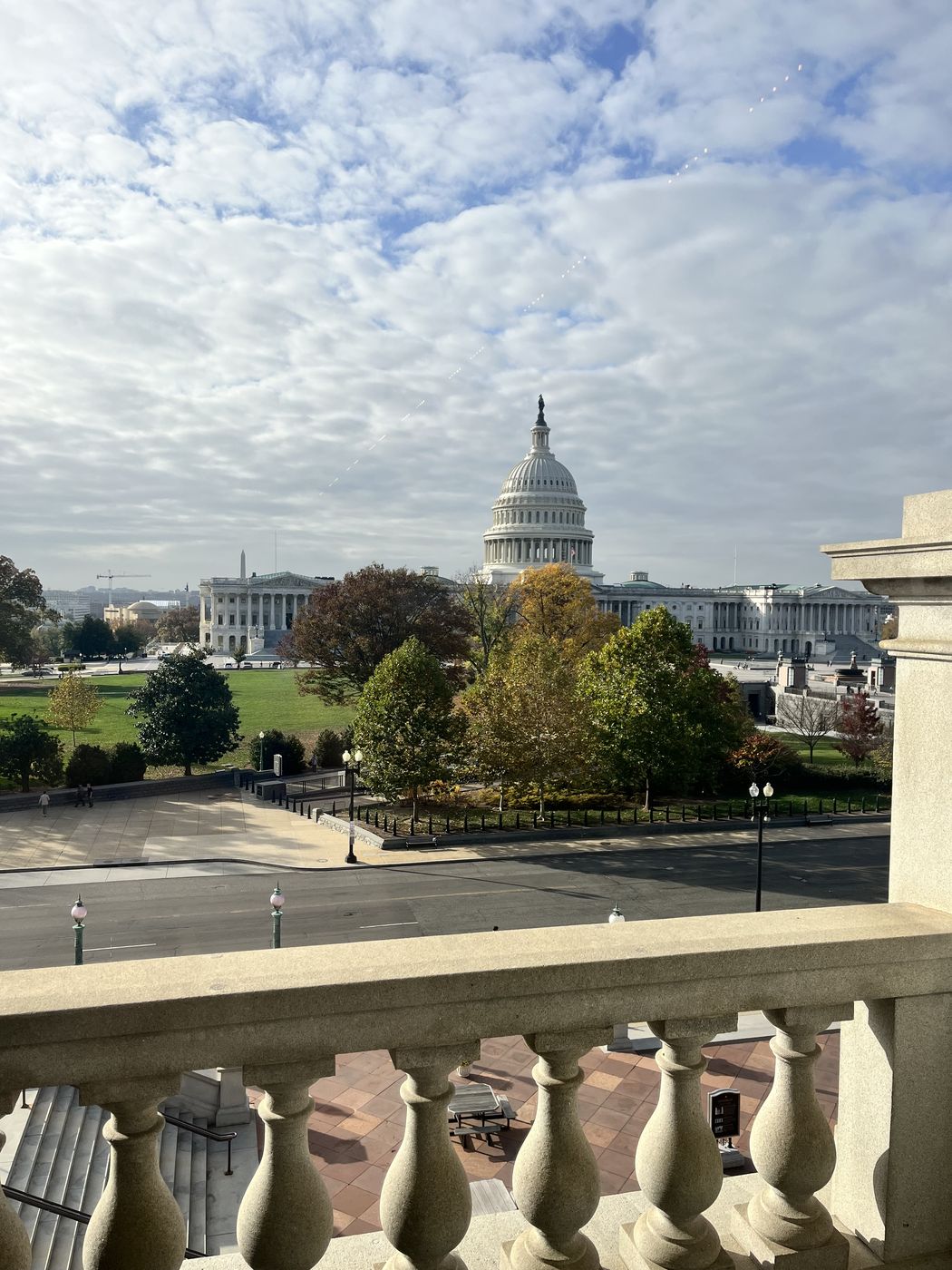 The U.S. Capitol framed by a stone balustrade under bright clouds