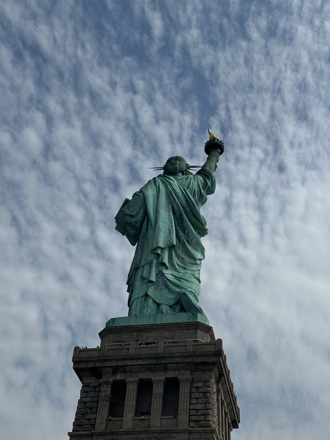 Statue of Liberty from below against rippled clouds