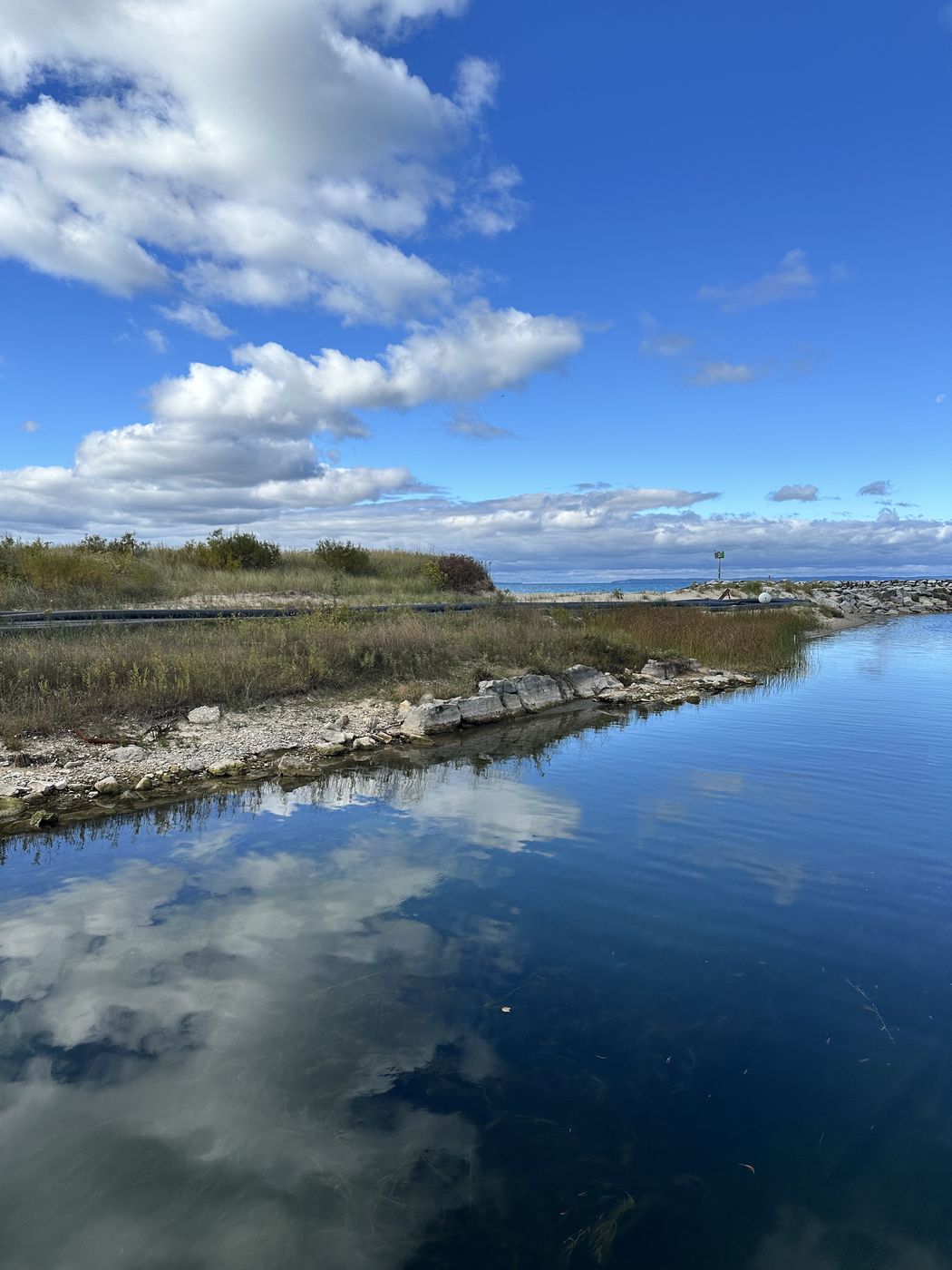 Clouds reflected in still shoreline water at Leland