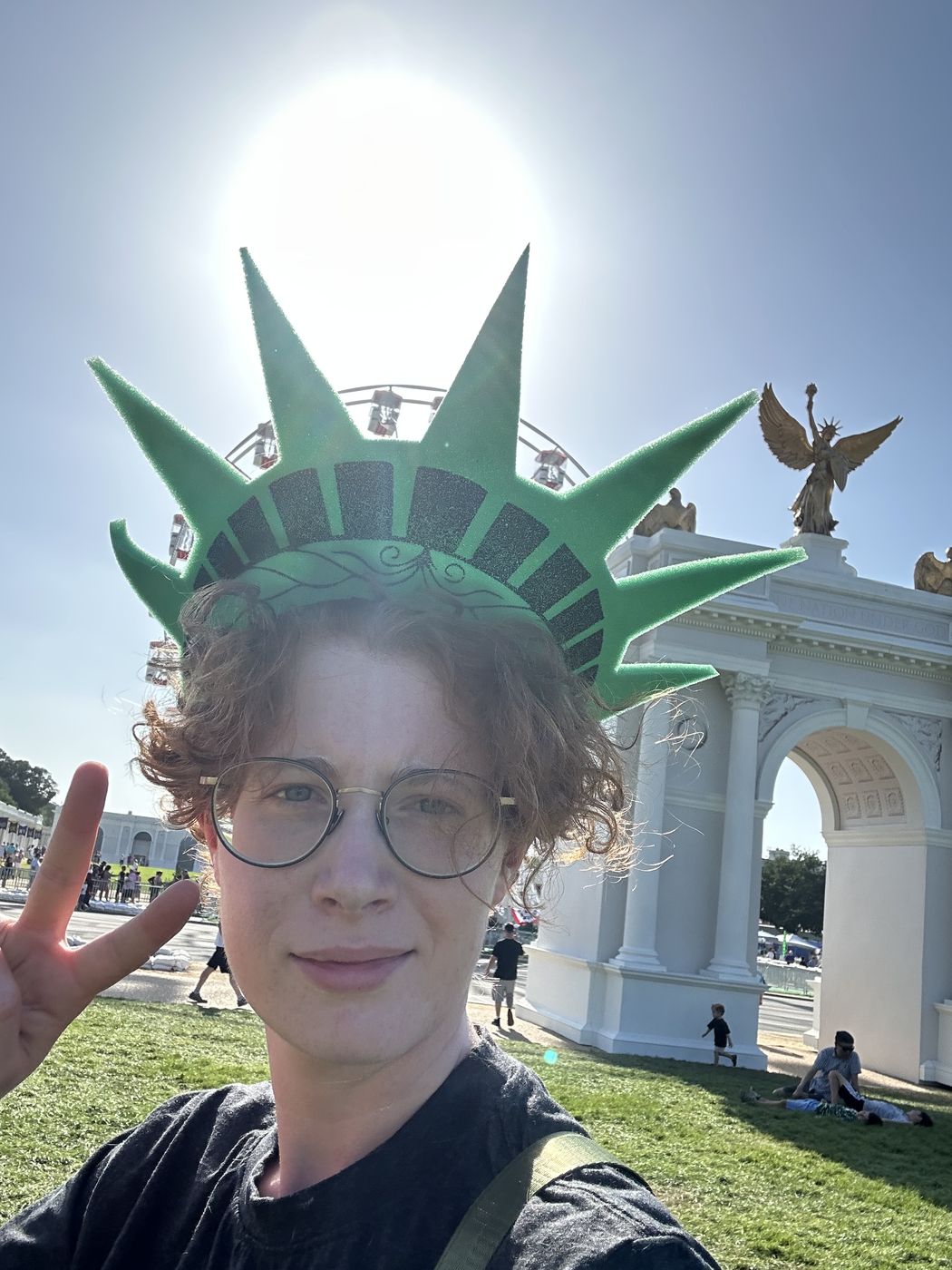 Selfie wearing a Statue of Liberty crown headband with the sun flaring directly behind it